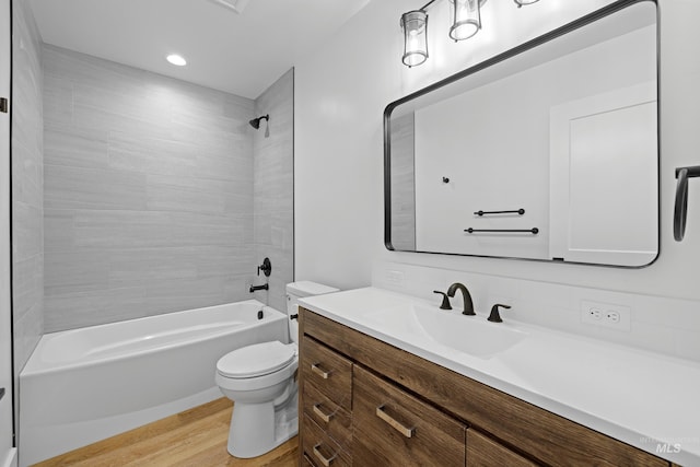 full bathroom with vanity, tiled shower / bath, hardwood / wood-style flooring, and toilet