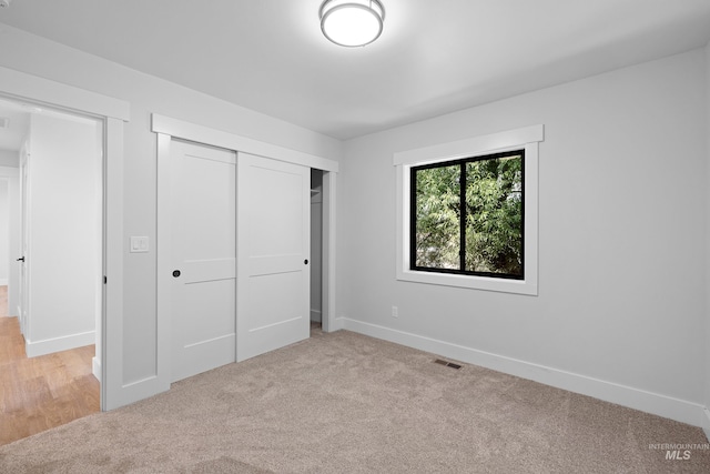 unfurnished bedroom with light carpet and a closet