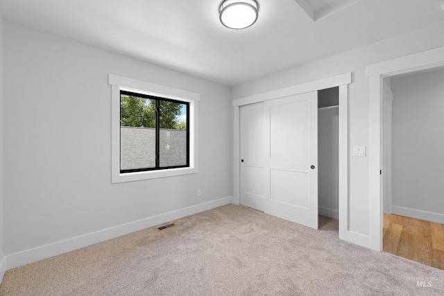 unfurnished bedroom with light carpet and a closet