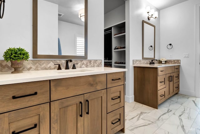 bathroom featuring two vanities, marble look tiles, and tasteful backsplash