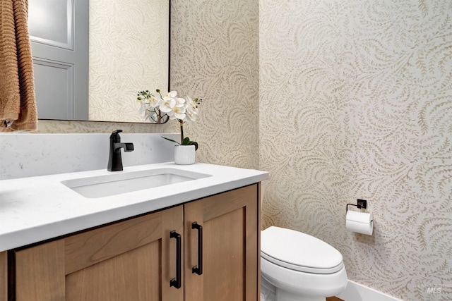 bathroom featuring wallpapered walls, toilet, and vanity