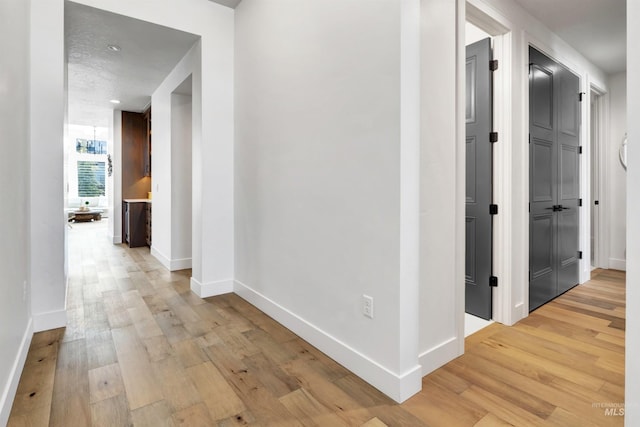 corridor with light wood-style flooring and baseboards