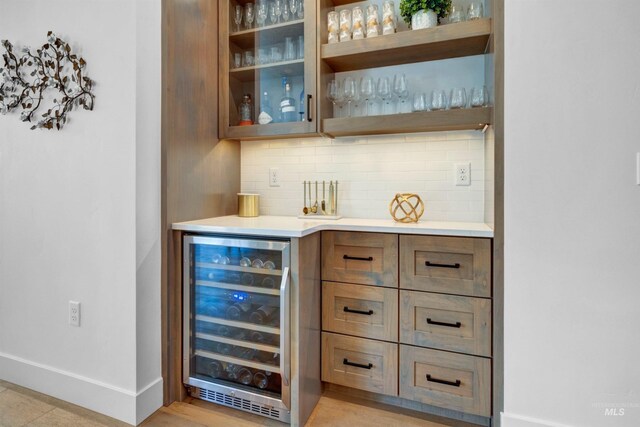 indoor dry bar with beverage cooler, backsplash, and baseboards