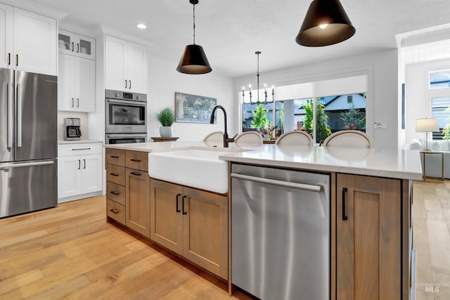 kitchen featuring appliances with stainless steel finishes, a sink, recessed lighting, light wood-style floors, and white cabinets