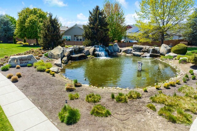 water view featuring a garden pond and fence