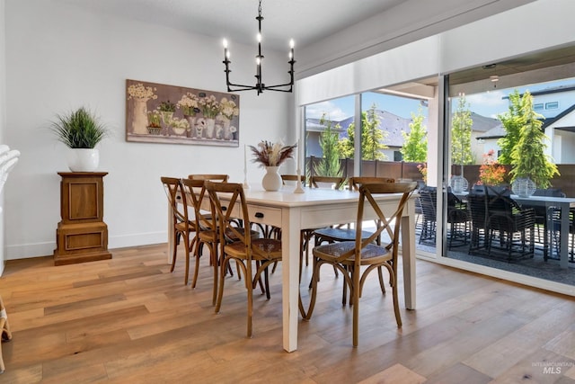 dining room with a chandelier, light wood-style flooring, and baseboards
