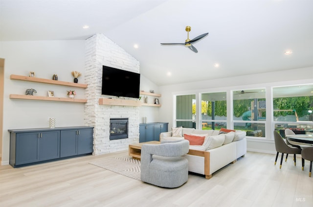 living room featuring light hardwood / wood-style floors, brick wall, a stone fireplace, high vaulted ceiling, and ceiling fan