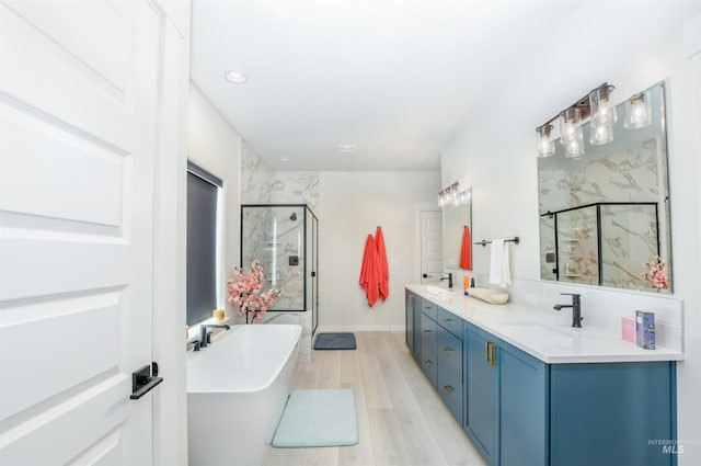 bathroom with dual bowl vanity, separate shower and tub, and wood-type flooring