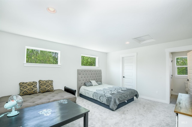 carpeted bedroom with ensuite bathroom and multiple windows