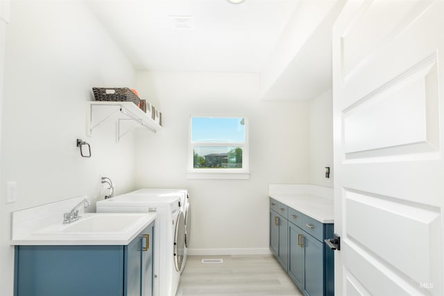 laundry area featuring cabinets, light wood-type flooring, and washing machine and clothes dryer