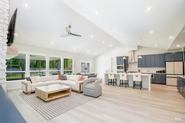 living room with brick wall, light hardwood / wood-style floors, high vaulted ceiling, and ceiling fan