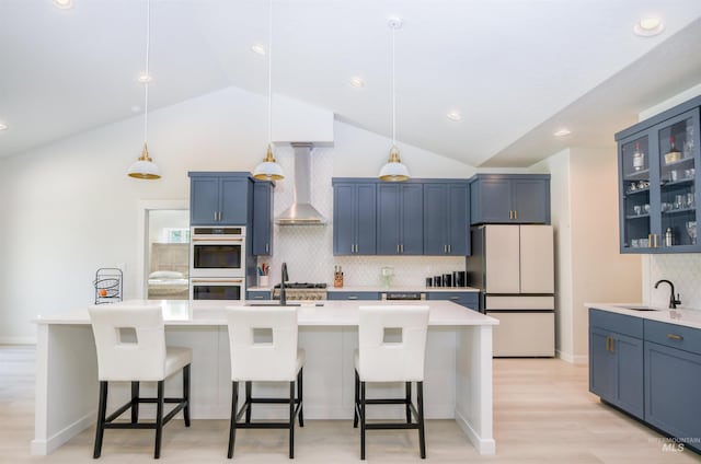 kitchen featuring tasteful backsplash, blue cabinetry, light wood-type flooring, wall chimney exhaust hood, and double oven