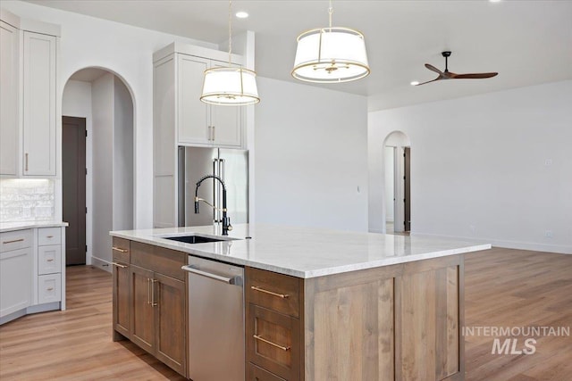 1967 Red Rock Way, Twin Falls, ID 83301 - kitchen featuring arched walkways, stainless steel appliances, ceiling fan, light wood-style floors, and light stone countertops