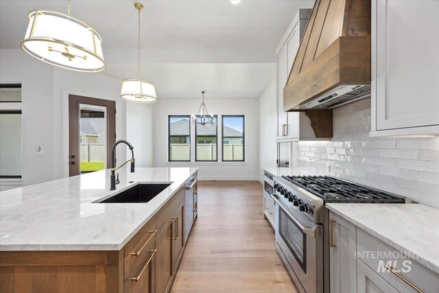 1967 Red Rock Way, Twin Falls, ID 83301 - kitchen with appliances with stainless steel finishes, premium range hood, light wood-type flooring, backsplash, and light stone countertops