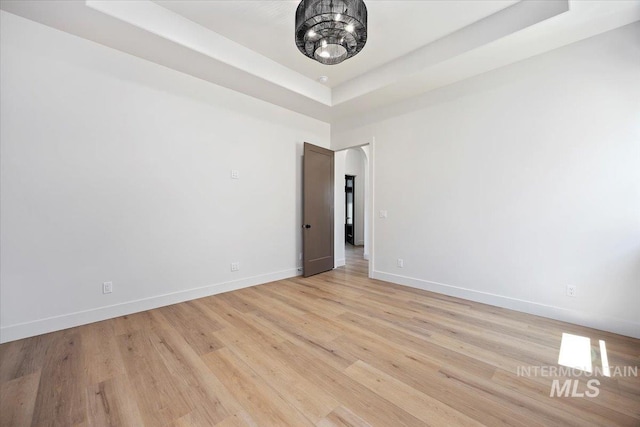 1967 Red Rock Way, Twin Falls, ID 83301 - spare room featuring a tray ceiling, light wood-style flooring, and a chandelier
