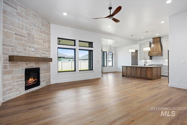 1967 Red Rock Way, Twin Falls, ID 83301 - unfurnished living room with a ceiling fan, a stone fireplace, light wood-type flooring, and recessed lighting