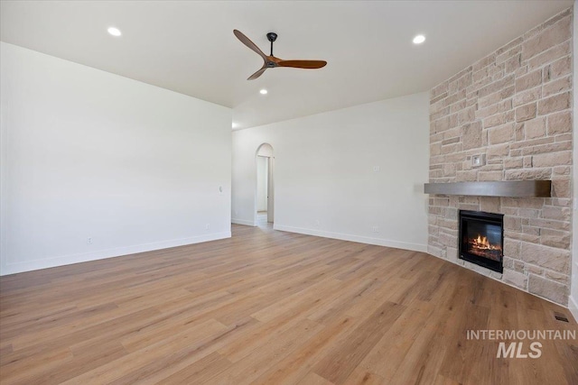 1967 Red Rock Way, Twin Falls, ID 83301 - unfurnished living room with ceiling fan, a stone fireplace, wood finished floors, arched walkways, and recessed lighting