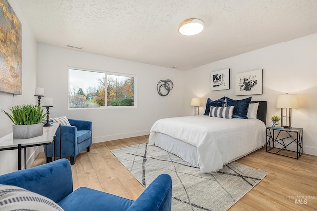 bedroom with a textured ceiling and light wood-type flooring