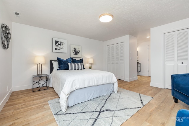 bedroom featuring wood-type flooring and two closets