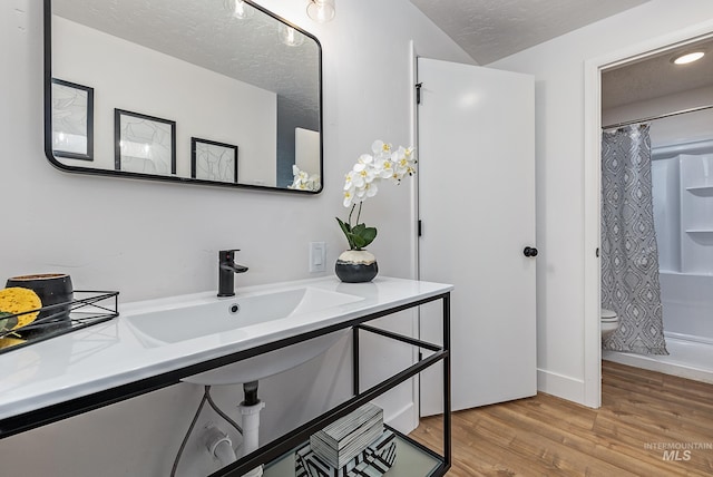 full bathroom with toilet, sink, shower / tub combo, a textured ceiling, and hardwood / wood-style floors