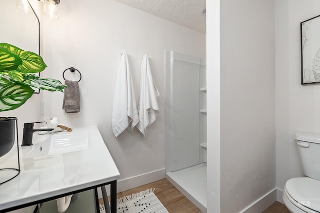 bathroom with toilet, sink, a shower, a textured ceiling, and hardwood / wood-style flooring