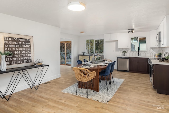 dining space with sink and light wood-type flooring