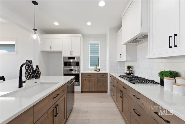 7625 W Whisper Ridge Dr, Meridian, ID 83646 - kitchen with stainless steel appliances, custom exhaust hood, backsplash, light wood-style floors, and recessed lighting