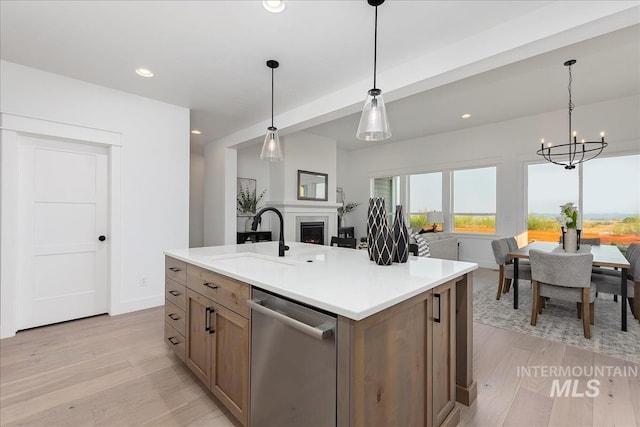 7625 W Whisper Ridge Dr, Meridian, ID 83646 - kitchen with stainless steel dishwasher, light wood finished floors, recessed lighting, a lit fireplace, and hanging light fixtures