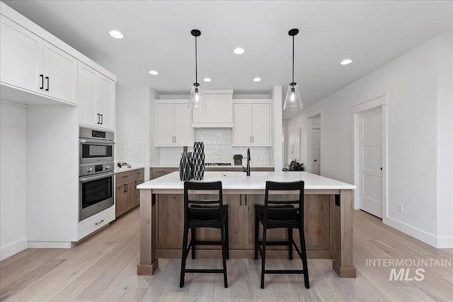 7625 W Whisper Ridge Dr, Meridian, ID 83646 - kitchen featuring light wood finished floors, backsplash, white cabinetry, light countertops, and double oven