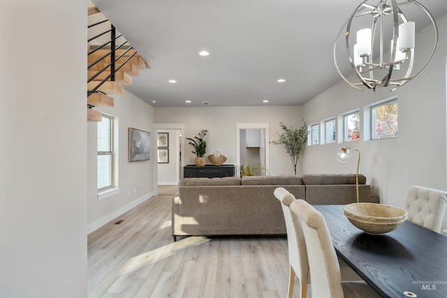 dining area with light wood-type flooring and a notable chandelier