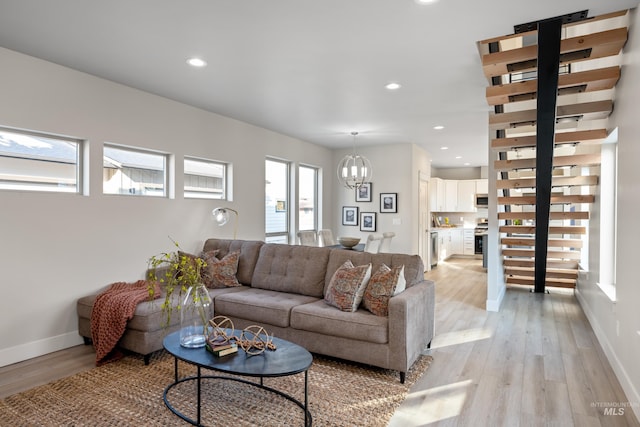 living room featuring light hardwood / wood-style floors, a healthy amount of sunlight, and an inviting chandelier