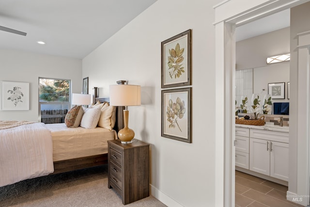 bedroom featuring sink, light carpet, ceiling fan, and ensuite bath