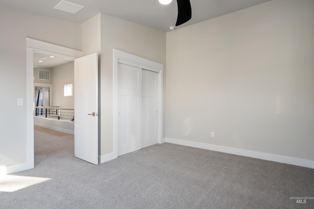 unfurnished bedroom featuring light carpet, ceiling fan, and a closet