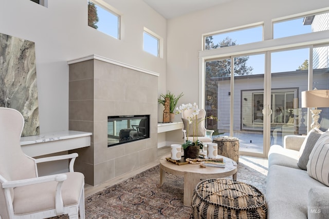 living room with a wealth of natural light, a high ceiling, and a tile fireplace