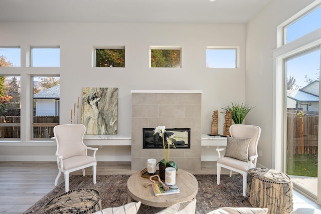 interior space with hardwood / wood-style flooring, a tiled fireplace, and a healthy amount of sunlight