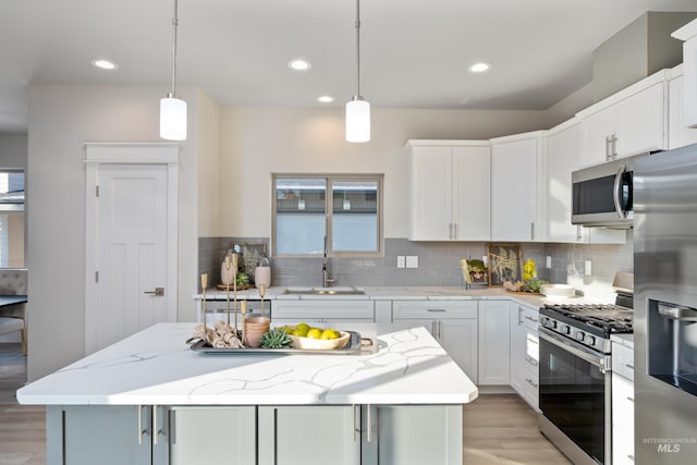 kitchen with a kitchen island, white cabinetry, appliances with stainless steel finishes, and hanging light fixtures