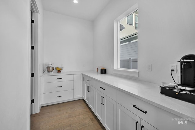 kitchen with light stone counters, light hardwood / wood-style flooring, and white cabinets