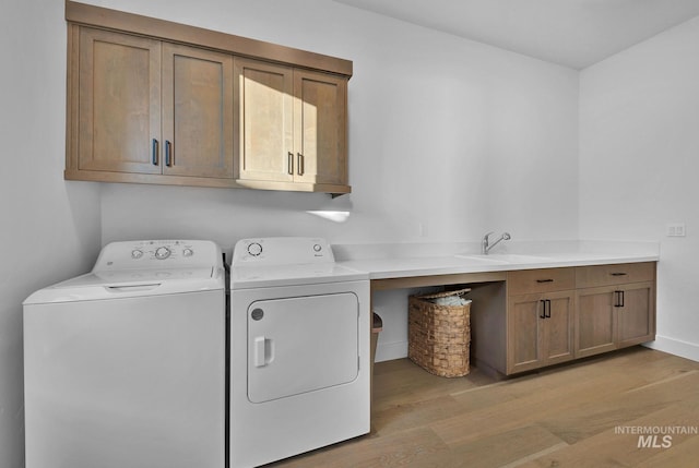 laundry room with light hardwood / wood-style flooring, cabinets, and washing machine and clothes dryer