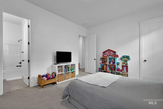 bedroom with ensuite bathroom and light colored carpet