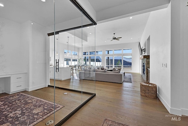 living room with a fireplace, wood-type flooring, and ceiling fan