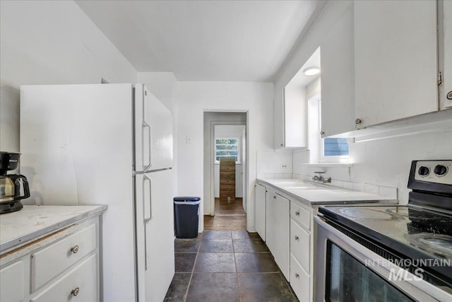 202E 2nd St, Shoshone, ID 83352 - kitchen with electric range, white cabinets, light countertops, and freestanding refrigerator