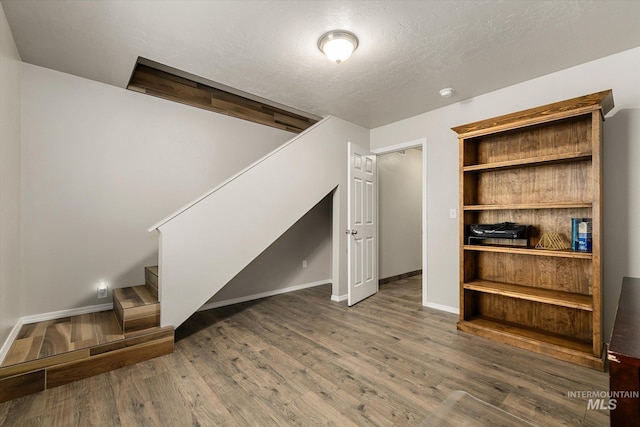1814 N Rosedust Dr, Kuna, ID 83634 - unfurnished living room featuring stairs, wood finished floors, baseboards, and a textured ceiling