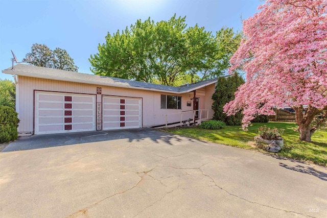 ranch-style home featuring an attached garage, a front yard, and concrete driveway