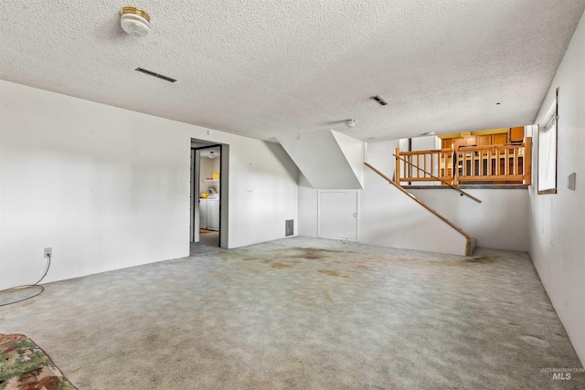 additional living space with carpet floors, a textured ceiling, and visible vents