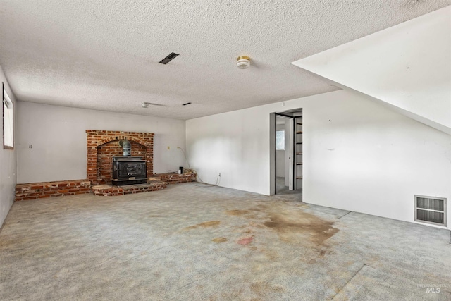 3709 11th St, Lewiston, ID 83501 - unfurnished living room featuring carpet floors, a wood stove, a textured ceiling, and visible vents