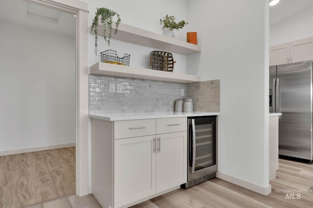 17869 N Onaway Ave, Nampa, ID 83686 - indoor dry bar with stainless steel refrigerator with ice dispenser, beverage cooler, tasteful backsplash, light wood-type flooring, and baseboards