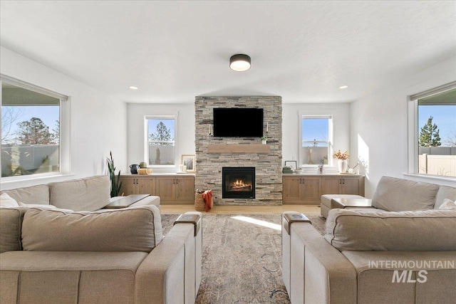 living room with light wood-style flooring, a wealth of natural light, recessed lighting, and a fireplace
