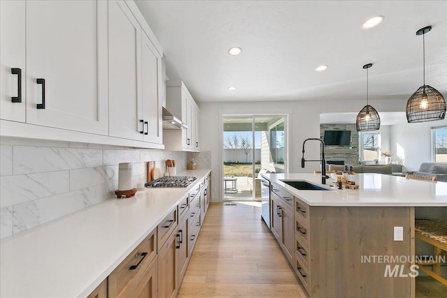 kitchen featuring a sink, stainless steel gas stovetop, a center island with sink, light wood-style flooring, and recessed lighting