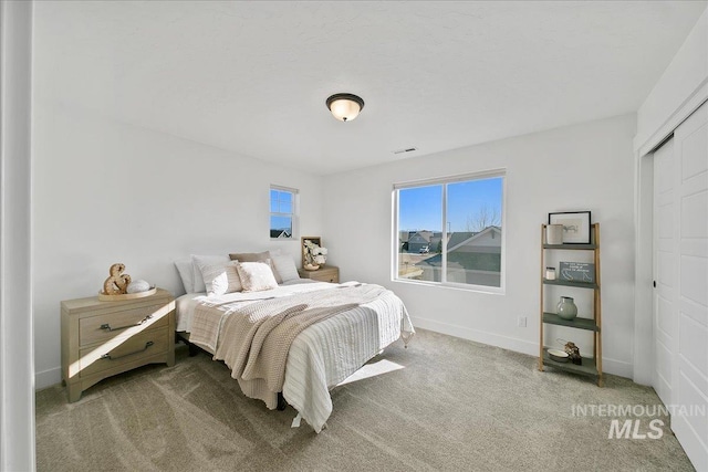 carpeted bedroom featuring visible vents, baseboards, and a closet