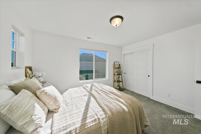 carpeted bedroom with baseboards, visible vents, and a closet